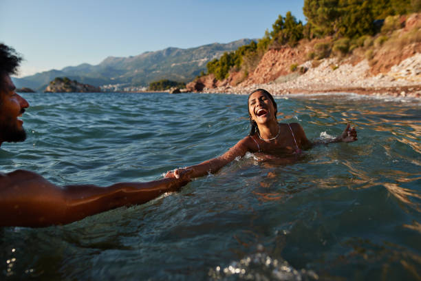 woman swimming with boyfriend in sea - travel stock pictures, royalty-free photos & images