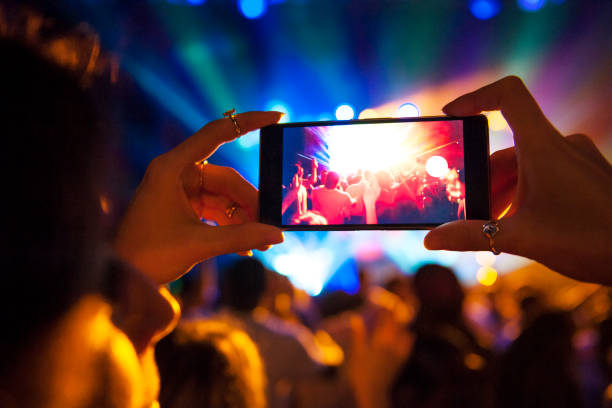 woman taking a photo with phone at music event - concert stock pictures, royalty-free photos & images