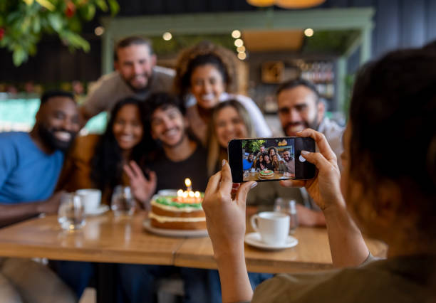 woman taking a picture of a group of people celebrating a birthday - home decoration stock pictures, royalty-free photos & images