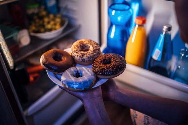 woman taking donuts out of the fridge - junk food stock pictures, royalty-free photos & images