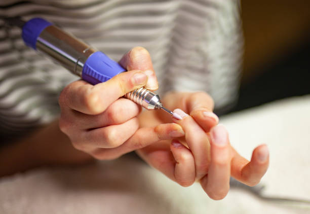 woman using electric nail file to clean cuticles. - nails art stock pictures, royalty-free photos & images