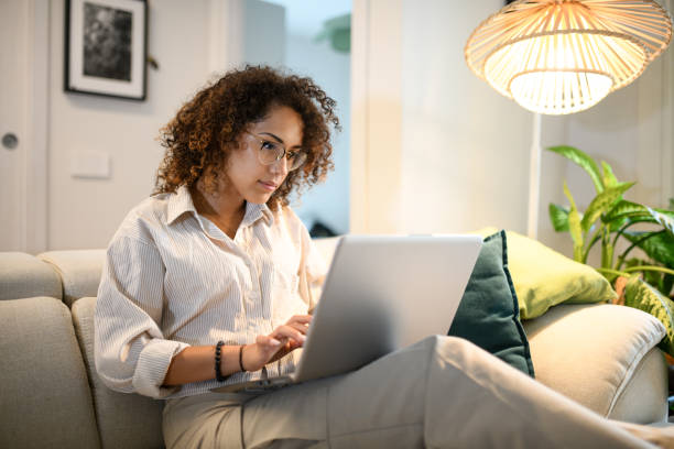 woman using laptop on sofa - home decoration photos et images de collection