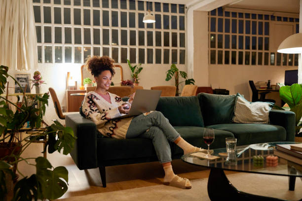 woman using laptop on sofa in living room - home decoration stock pictures, royalty-free photos & images