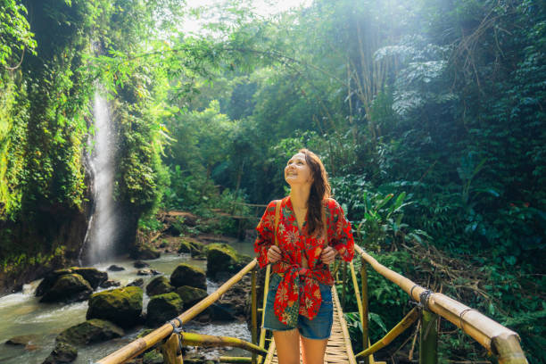 woman walking near the refreshing waterfall on bali - travel stockfoto's en -beelden