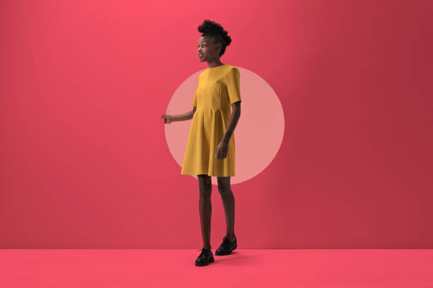 woman walking out from woman peeking out of round opening in coloured wall - fashion stock-fotos und bilder