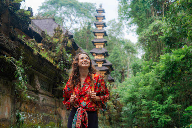 woman walking past the temple in the jungles in bali - travel stock-fotos und bilder
