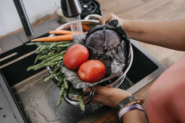 woman washing fresh vegetable in sink at home - food stock-fotos und bilder