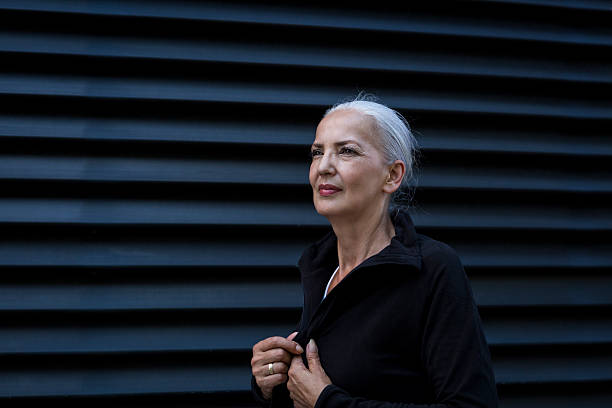 woman wearing black tracksuit top in front of black background - fashion photos et images de collection