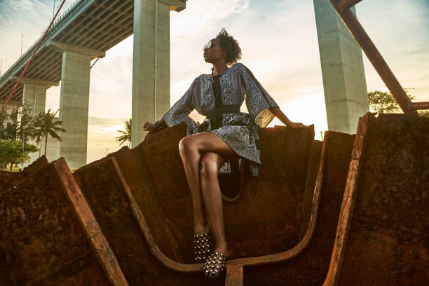 woman wearing dress and sitting on rusty ship wreck - fashion stock pictures, royalty-free photos & images