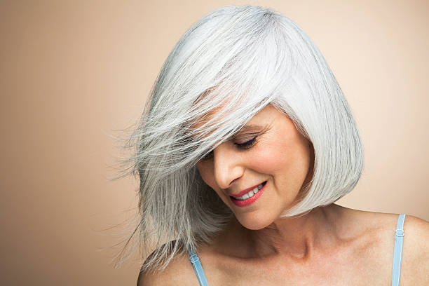 woman with a silvery,grey bob looking down. - hairstyle stock-fotos und bilder
