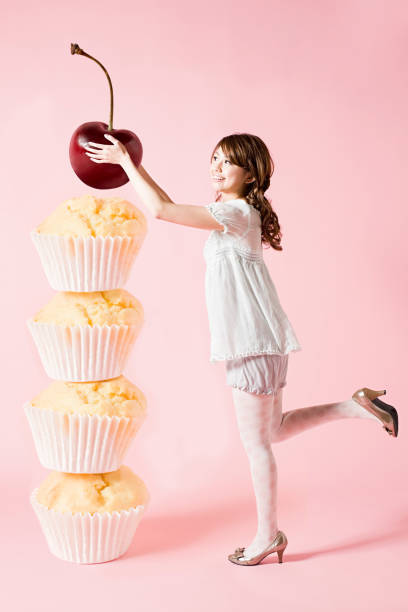 woman with cherry and cupcakes - junk food stockfoto's en -beelden