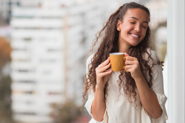 woman with closed eyes enjoying a cup of coffee - coffee stock pictures, royalty-free photos & images