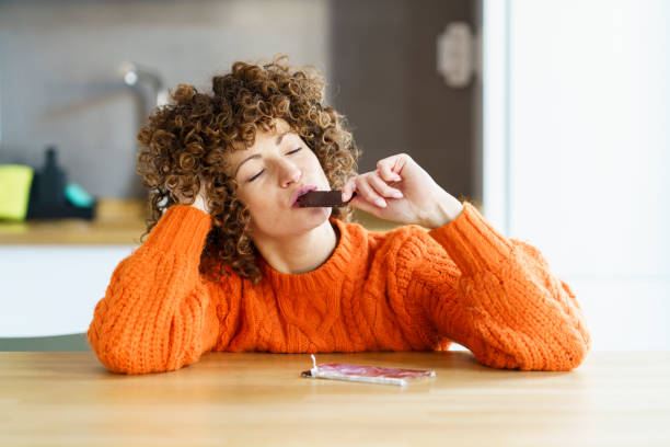 woman with eyes closed enjoying chocolate at home - food stock pictures, royalty-free photos & images