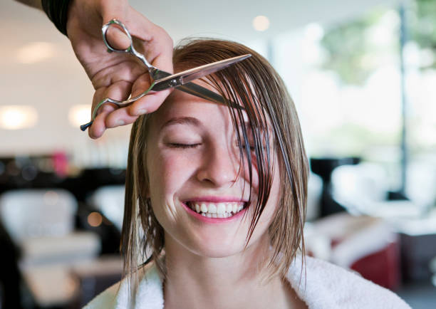 woman with eyes closed having her fringe cut off - hairstyle stock-fotos und bilder