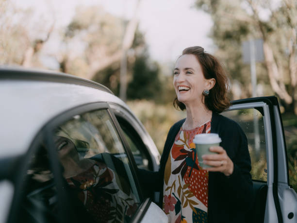woman with takeaway coffee getting in car - junk food stock pictures, royalty-free photos & images