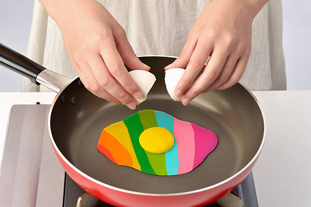 women bake in a frying pan colorful egg - food stock pictures, royalty-free photos & images
