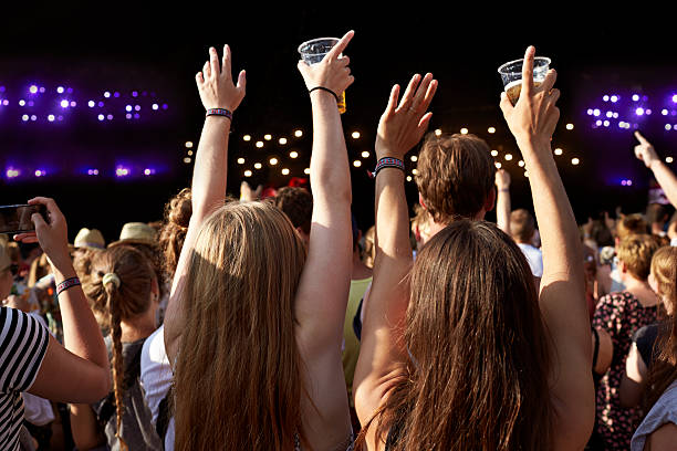 women with raised hands holding beer at concert - concert stock pictures, royalty-free photos & images