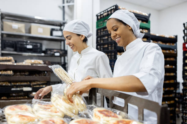 women working at an industrial bakery doing quality control on packages of bread - food stock pictures, royalty-free photos & images