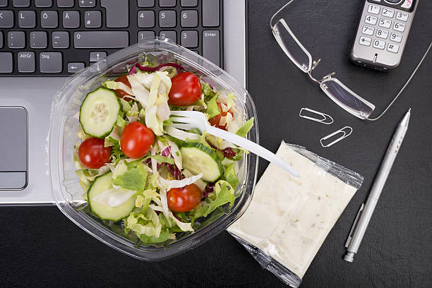 workplace with mixed salad on laptop - junk food stock pictures, royalty-free photos & images