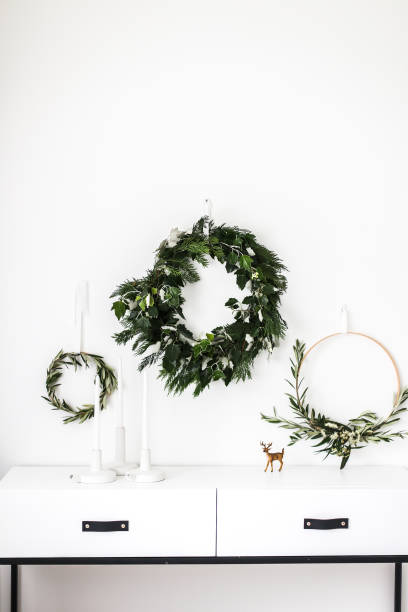 wreaths hanging on a wall by a sideboard - home decoration stock pictures, royalty-free photos & images
