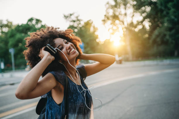young adult woman with afro hair dancing in the city at sunset while listening to music - concert stock pictures, royalty-free photos & images