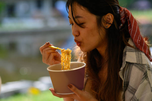 young asian woman eating instant noodles morning - junk food stock pictures, royalty-free photos & images