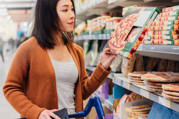 young asian woman picking up pizza in grocery store - junk food stock pictures, royalty-free photos & images