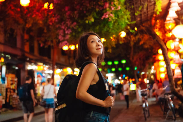 young asian woman with backpack walking at night market during chinese new year - travel stock-fotos und bilder