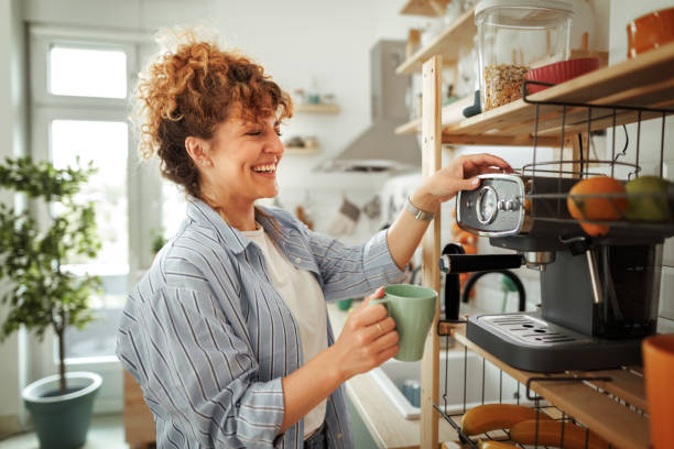 young beautiful smiling woman making coffee in a domestic kitchen - coffee stock pictures, royalty-free photos & images