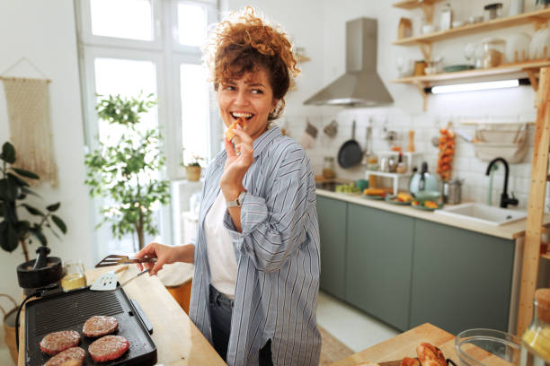 young beautiful woman making burgers in a domestic kitchen - food stock pictures, royalty-free photos & images
