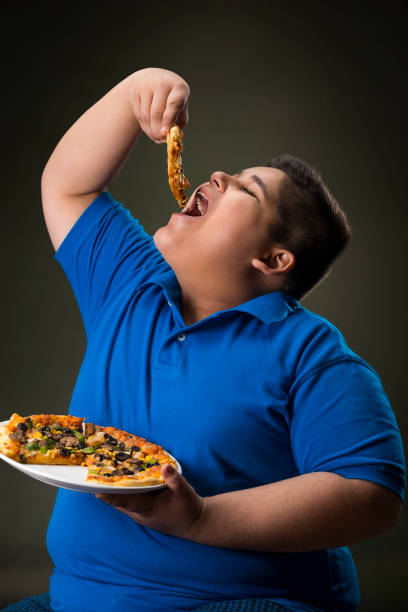 young boy having a slice of pizza. (obesity) - junk food stock pictures, royalty-free photos & images