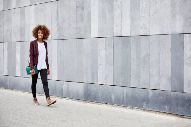 young businesswoman walking on sidewalk by wall - fashion stock pictures, royalty-free photos & images