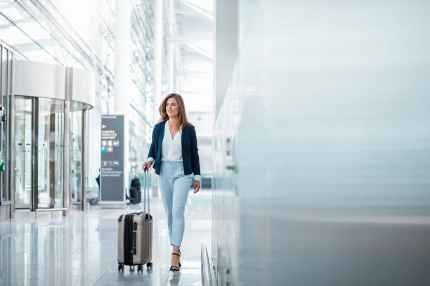 young businesswoman walking with luggage at the airport - travel stock pictures, royalty-free photos & images