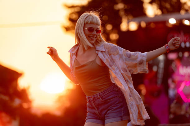 young carefree woman having fun while dancing on a music festival at sunset. - concert stock pictures, royalty-free photos & images
