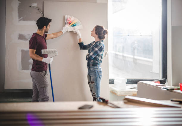 young couple choosing the right color for their wall while renovating apartment. - home decoration stock pictures, royalty-free photos & images