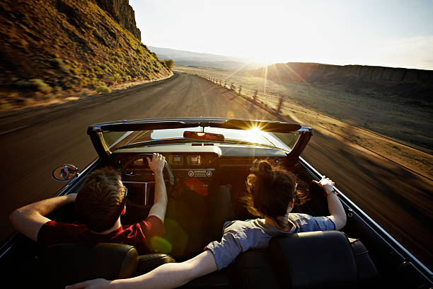 young couple driving convertible at sunset - travel stock pictures, royalty-free photos & images