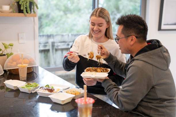 young couple enjoying takeaway food at home - junk food stock pictures, royalty-free photos & images