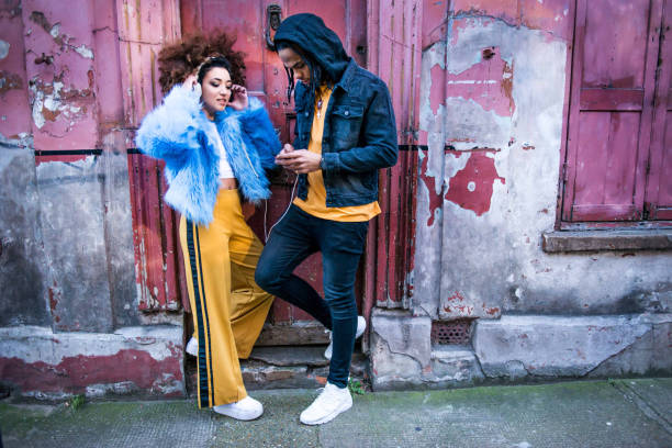 young couple listening to music through headphones on smartphone - fashion stock pictures, royalty-free photos & images