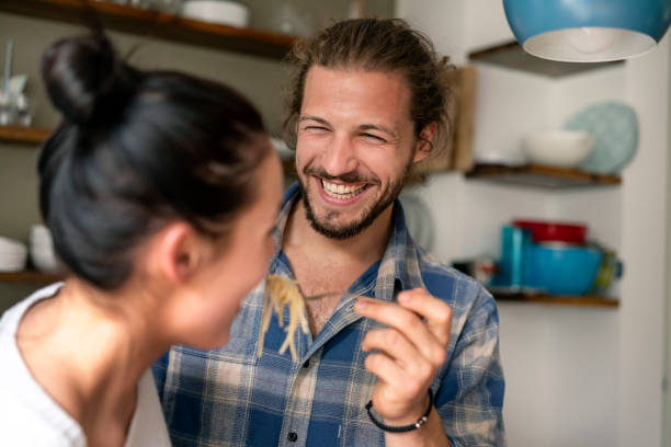 young couple preparing food together, tasting spaghetti - food stock pictures, royalty-free photos & images