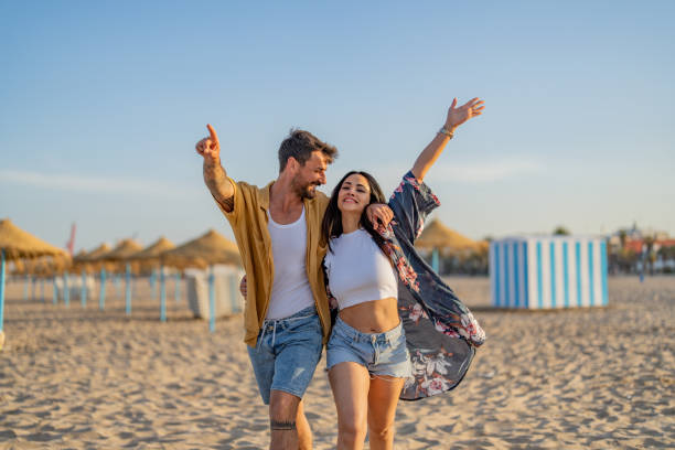young couple spending time together at the beach, celebrating success. - travel stock pictures, royalty-free photos & images
