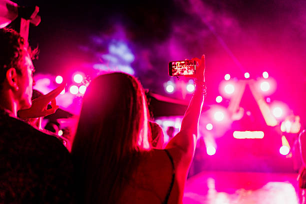 young couple taking a selfie during party outdoors - concert stockfoto's en -beelden