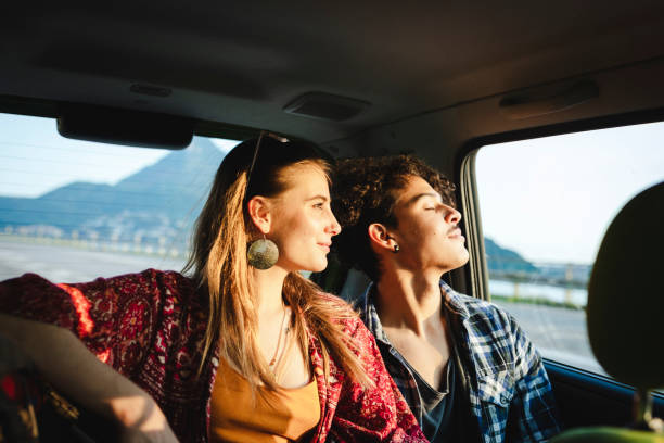 young couple traveling by car, sunset light - travel stock pictures, royalty-free photos & images