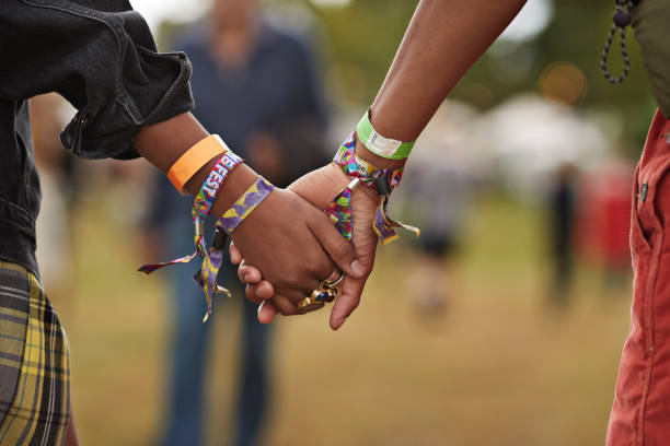 young couple with wristbands holding hands - concert stock pictures, royalty-free photos & images