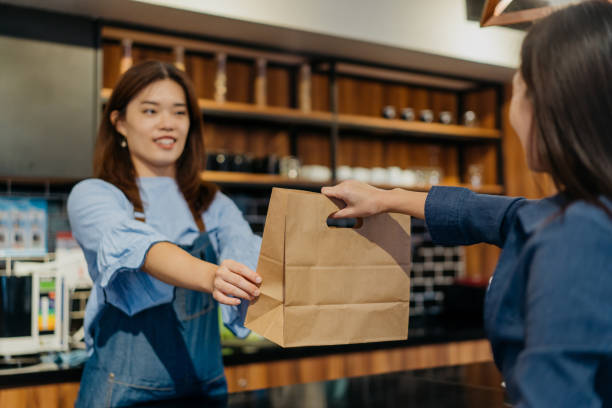 young female barista giving take out food to customer in cafe - junk food stock pictures, royalty-free photos & images