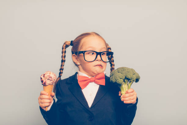 young female nerd holds ice cream and broccoli - junk food stock pictures, royalty-free photos & images