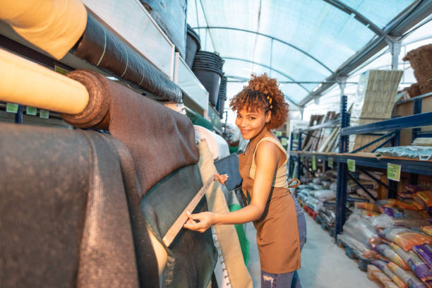 young female worker measuring and looking at blackout tarpaulins for fences, concealment fabric for home perimeter - garden decoration stock pictures, royalty-free photos & images