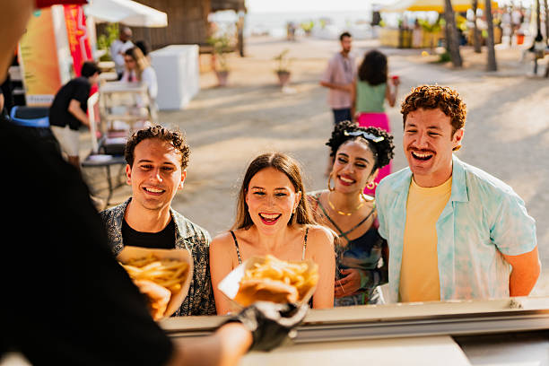 young friends buying snacks outdoors - concert stock pictures, royalty-free photos & images