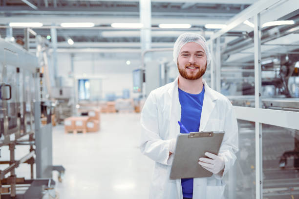 young handsome smiling scientist with clipboard posing in factory - food stock pictures, royalty-free photos & images
