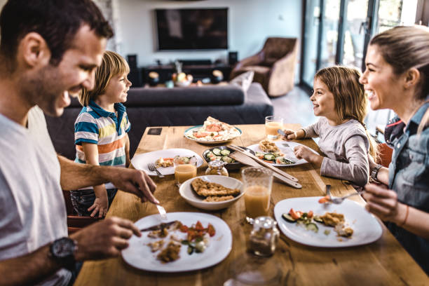 young happy family talking while having lunch at dining table. - food stock pictures, royalty-free photos & images