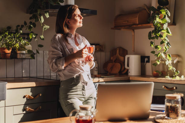 young happy woman drinking coffee on the kitchen in the morning. - coffee stock pictures, royalty-free photos & images